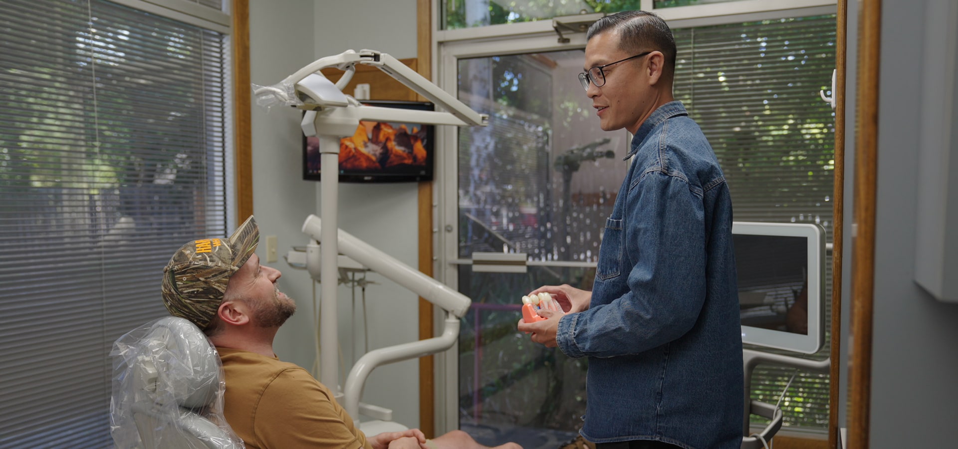 Dentist and his happy colleague in a dental chair are smiling