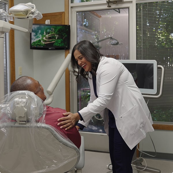 Top dentist is shaking hands with a happy patient in a dental chair
