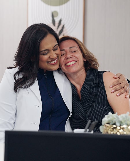 Two women are smiling and hugging
