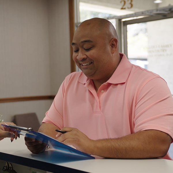 A man is happily smiling while filling a patient form